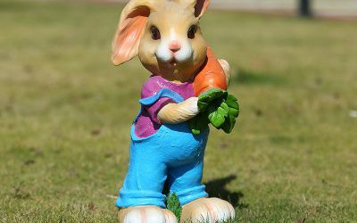 景区草坪中站立着一只抱胡萝卜的玻璃钢卡通兔子雕塑