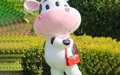 花园里一只拿包的玻璃钢彩绘卡通仿真动物牛雕塑