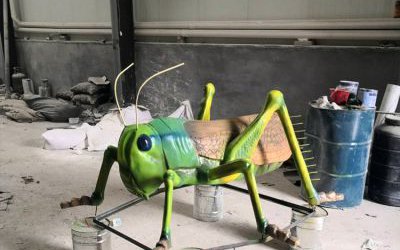 公园里摆放的棕色翅膀的玻璃钢彩绘蚱蜢雕塑