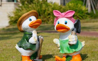 草地上手拿锄头和抗铲子的两只玻璃钢彩绘鸭子雕塑