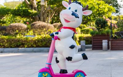 幼儿园卡通玻璃钢彩绘骑滑板车的小奶牛雕塑